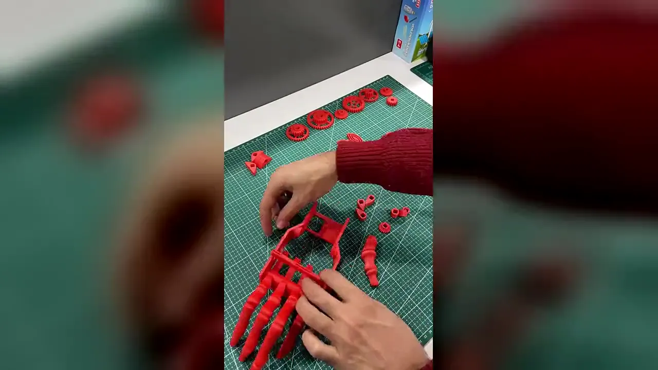 CEZERİ ROBOTECH atölyesinde 3D yazıcıyla basılan eklemli el projesinin parçaları ve öğrencilere demonte verilen setin montajı